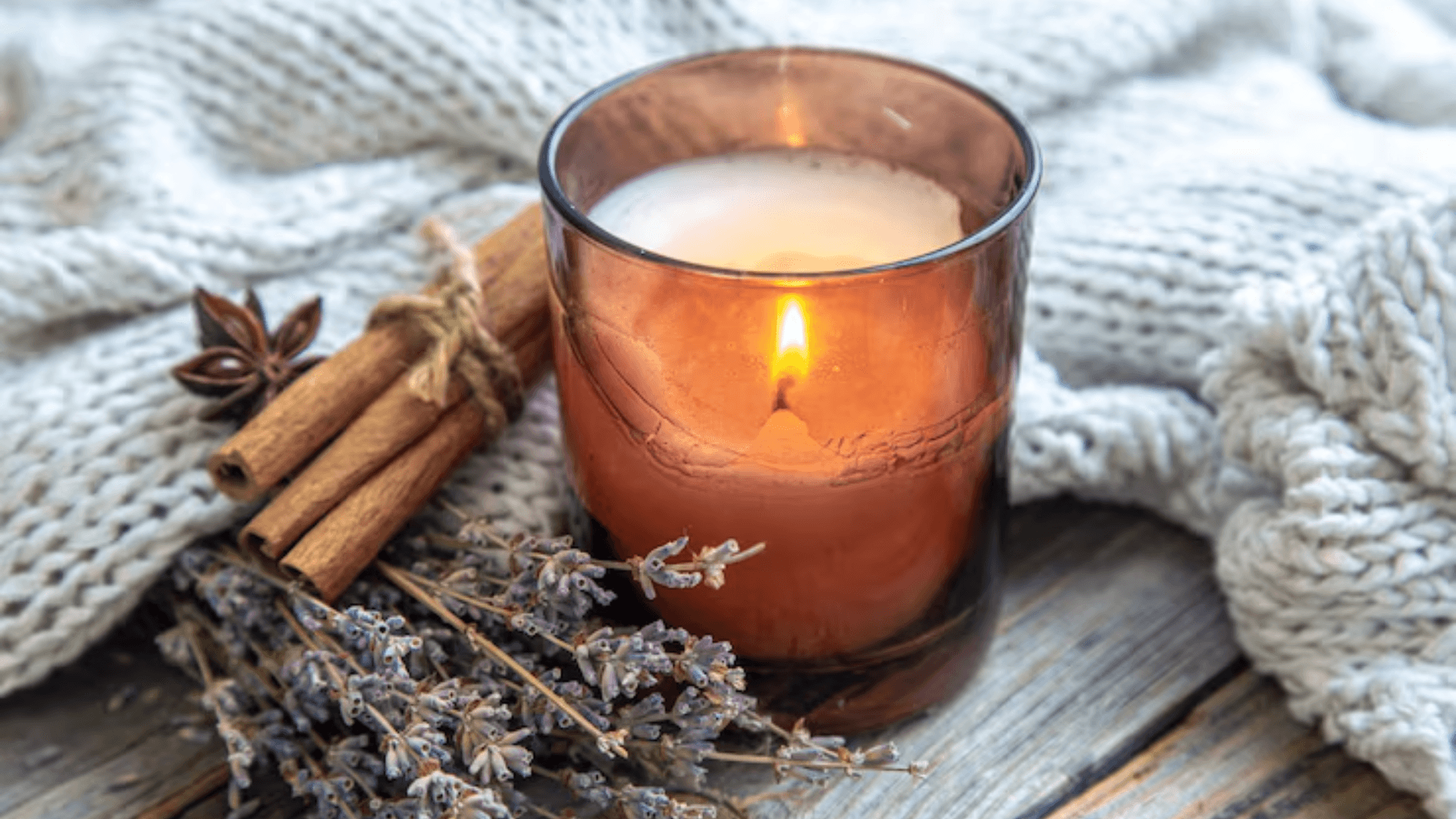A beautiful scented candle on the table with cinnamon sticks